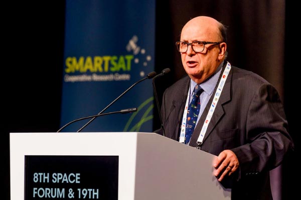 Man speaking at 8th space forum in front of SmartSat banner